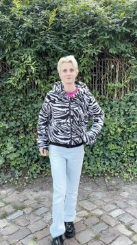 Fehér és fekete csíkos polárdzseki kapucnival, cipzárral elöl, és bordázott mandzsettákkal. Világoskék nadrág és fekete cipő egészíti ki a szettet.
