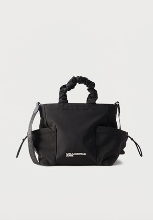 Sac à main en tissu noir avec poignées froncées, deux poches latérales, bandoulière réglable et logo blanc KARL LAGERFELD JEANS sur le devant.