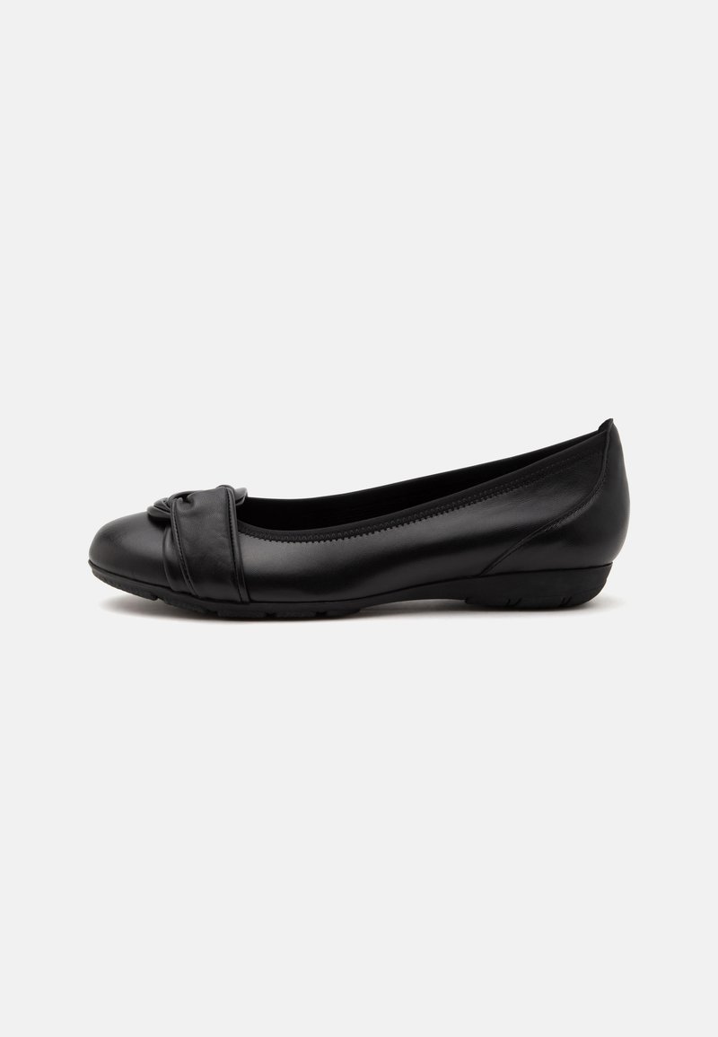 Chaussure plate noire pour femme avec un petit talon et une sangle décorative plissée sur la zone des orteils sur un fond clair.