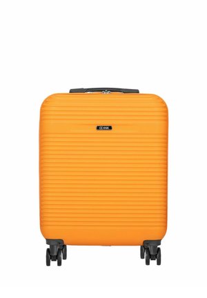 Jasnopomarańczowa, twarda walizka z poziomymi rowkami, czarną rączką, czterema czarnymi kołami oraz logo marki na środku przedniej części.