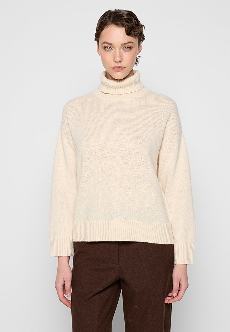 Beige Rollkragenpullover aus grobem Strick mit lockerer Passform und geripptem Saum. Lange Ärmel mit überschnittenen Schultern, strukturierte Oberfläche.