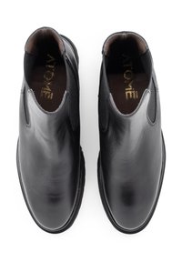 Schwarze Leder-Stiefeletten mit elastischen Seitenteilen, abgerundetem Zehenbereich, glatter Textur und flacher Sohle. Markenname innen in Gold geprägt.