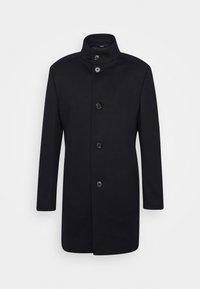 Cappotto nero con colletto alto, chiusura a cinque bottoni, vestibilità su misura e tessuto morbido. Design minimale senza motivi o accenti visibili.