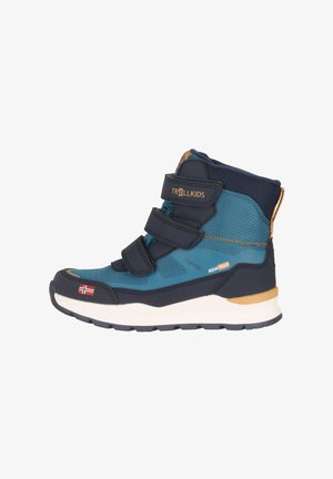 Blue and navy waterproof boot with three Velcro straps, textured side panels, and a white sole with gold accents. Features a flag detail.