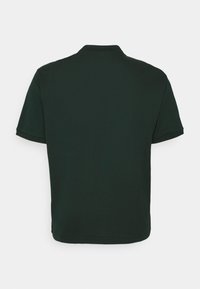 Polo-shirt vert foncé avec un col classique, des manches courtes et un ourlet droit avec des fentes sur les côtés pour plus de liberté de mouvement.