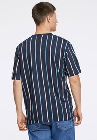 Marineblauwe t-shirt met verticale strepen in wit en lichtblauw. Relaxte pasvorm, korte mouwen, ronde halslijn, zacht katoen.
