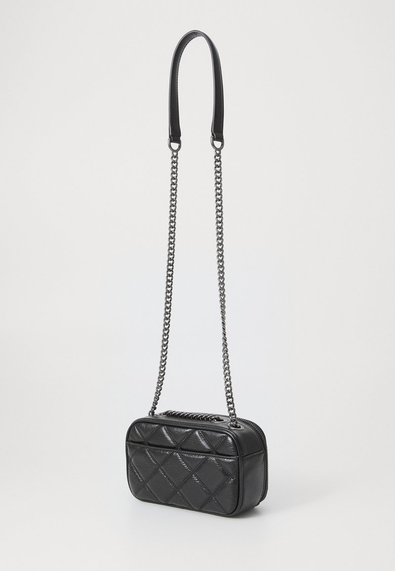 Sac à main en cuir matelassé noir de forme rectangulaire, doté d'une courte bandoulière noire et d'une chaîne en argent pour un port en bandoulière. Fermeture à glissière.