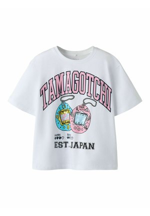Hvit kortermet skjorte med rosa "Tamagotchi" tekst, illustrasjoner av blå og rosa Tamagotchi-leker, og "EST. JAPAN" i svart tekst under.