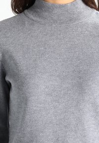 Maglione grigio a collo alto realizzato in un morbido tessuto a maglia testurizzata. Presenta un collo e polsini a coste, con una silhouette aderente.