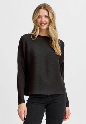 Black ribbed long-sleeve top with a relaxed fit, featuring a round neckline and side slits, paired with dark denim jeans.