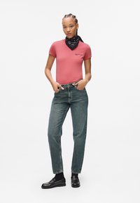Rosa tettskjorte, høy midje falmede blå jeans, svart bandana og svarte loafers med metalliske nagler. Minimalistisk design med casual stil.