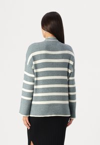 Gestreifter Cardigan aus weichem Strickstoff, mit abwechselnd grauen und weißen horizontalen Streifen, überschnittenen Schultern und geripptem Muster.