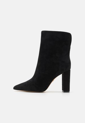 Mustmust jalats mustast sametist, terava varvaga ja paksu plokkningaga. Sile tekstuur ilma nähtavate mustrite või riistade detailideta.