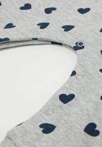 Tissu gris à finition texturée, ornée de petits cœurs bleu marine, et dotée d'une fermeture pression sur le côté.