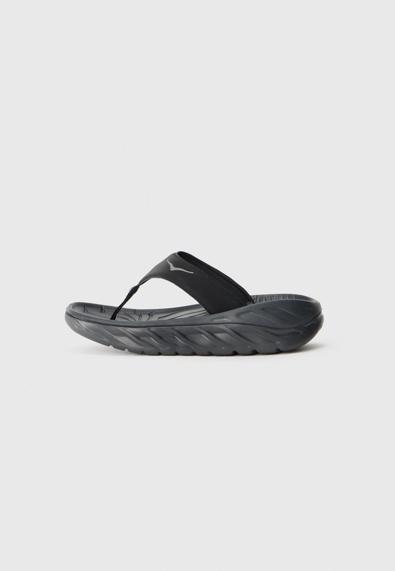 Tongs noires avec un semelle texturée et une semelle épaisse et rembourrée. Les lanières sont en matériau lisse avec un détail de logo.