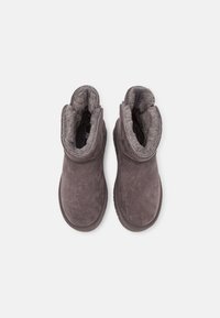 Botas de tobillo de ante gris con un interior suave forrado de pelo, un tacón bajo y detalle de costura a lo largo del cuello y la suela.