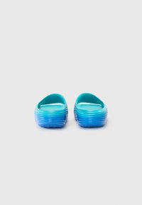 Clogs bleu et turquoise à enfiler avec une texture côtelée, une forme arrondie et un design de couleur dégradée, présentant un dos ouvert et des semelles texturées.