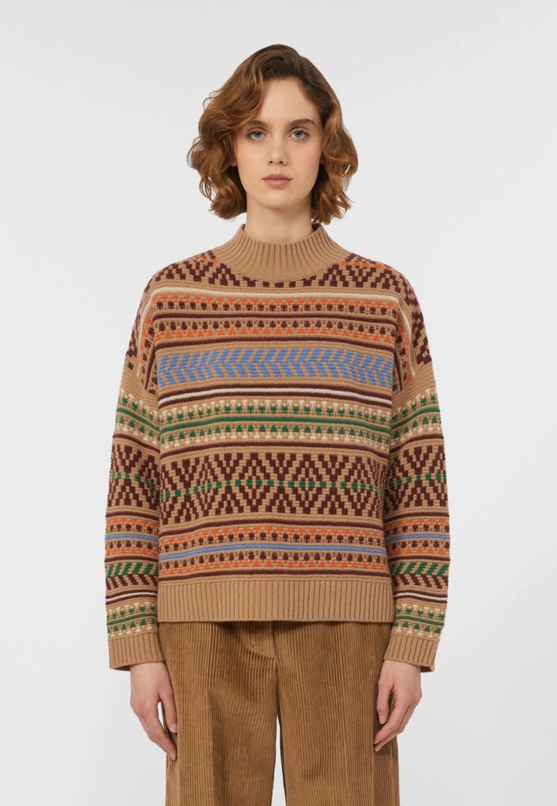 Maglione lavorato a maglia in color cammello con motivi geometrici multicolore, caratterizzato da un colletto rotondo a coste e maniche lunghe. Abbinato a pantaloni in velluto a coste.