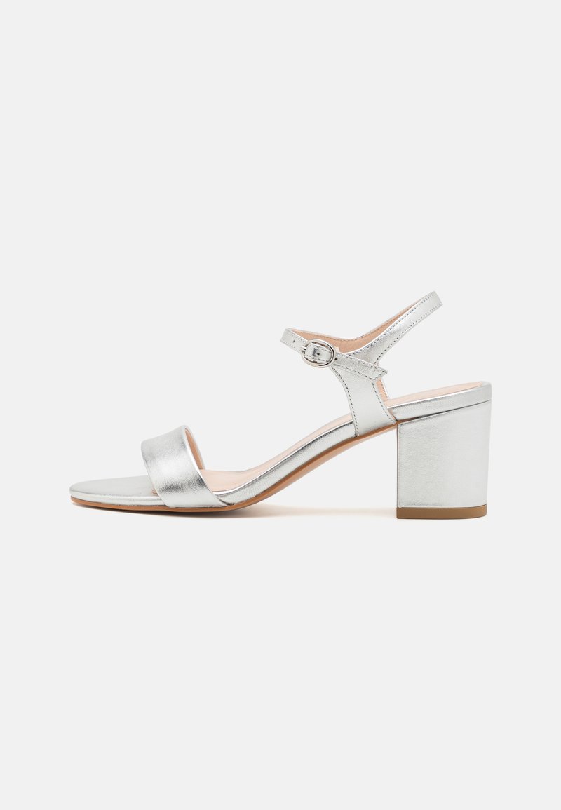 Hõbedased metallik blokknina sandaalid esirihma ja reguleeritava pahkluu rihmaga, millel on sile tekstuur ja minimalistlik disain.