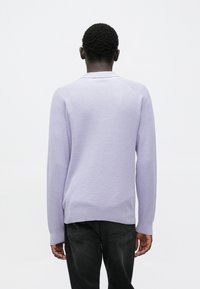 Suéter tejido de color púrpura claro con superficie texturizada, puños y bajo acanalados. Presenta un cuello redondo clásico y mangas largas.