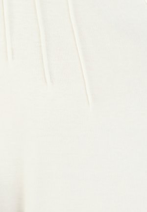 Close-up van wit geribd stof, met een zachte textuur, elastische tailleband en subtiele plooien, die de rekbaarheid en het comfort benadrukken.