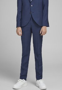 Navyblauwe op maat gemaakte pak met een gestructureerde afwerking, blazer met één knoop en slim-fit broek, gecombineerd met witte sneakers.