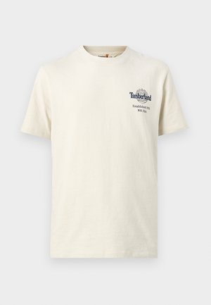 T-shirt à manches courtes et col rond de couleur blanc cassé avec petit logo Timberland et texte sur le côté gauche de la poitrine indiquant "Established 1973 NH, USA."