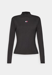 Svart långärmad polotröja i bomull, med en liten röd, vit och blå logotyp på bröstområdet. Slät textur.