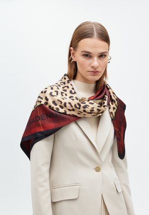 Silk scarf featuring a leopard print design on a beige background, with red and black accents and geometric patterns along the edges.