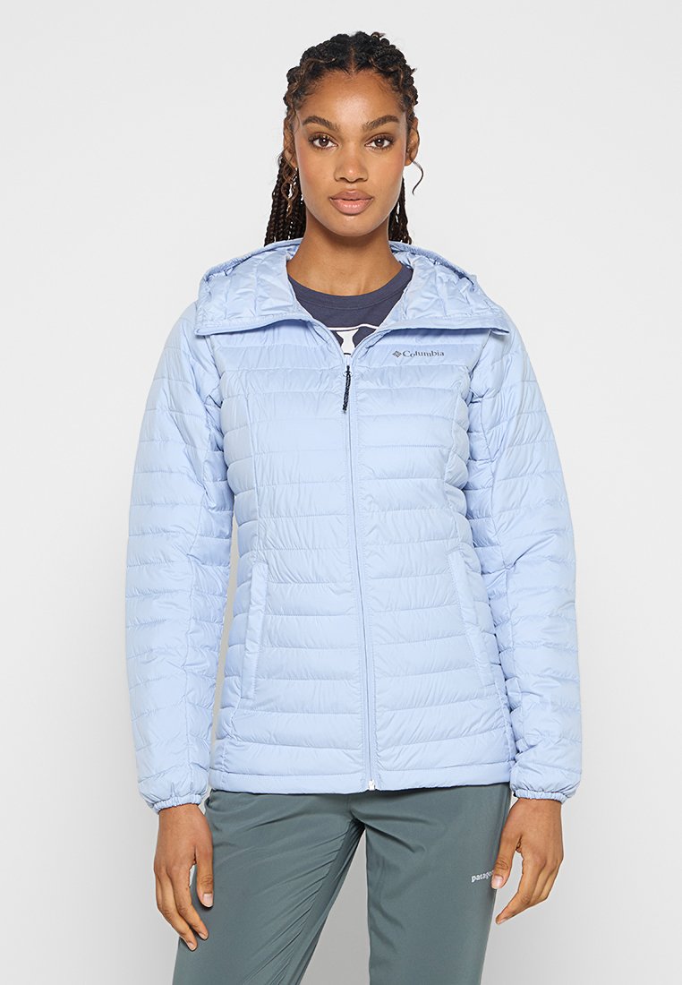 Giacca isolante azzurro chiaro con cappuccio, apertura centrale con zip e polsini elasticizzati. Presenta pannelli cuciti e due tasche laterali. Logo Columbia sul petto.