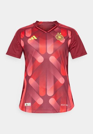 Camiseta deportiva roja de mangas cortas, con un patrón geométrico en naranja, cuello en V, tres franjas amarillas en los hombros y un escudo.
