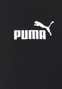 Tessuto nero con il logo bianco "PUMA" e una silhouette di puma in salto sopra di esso, caratterizzato da una texture liscia e uniforme.