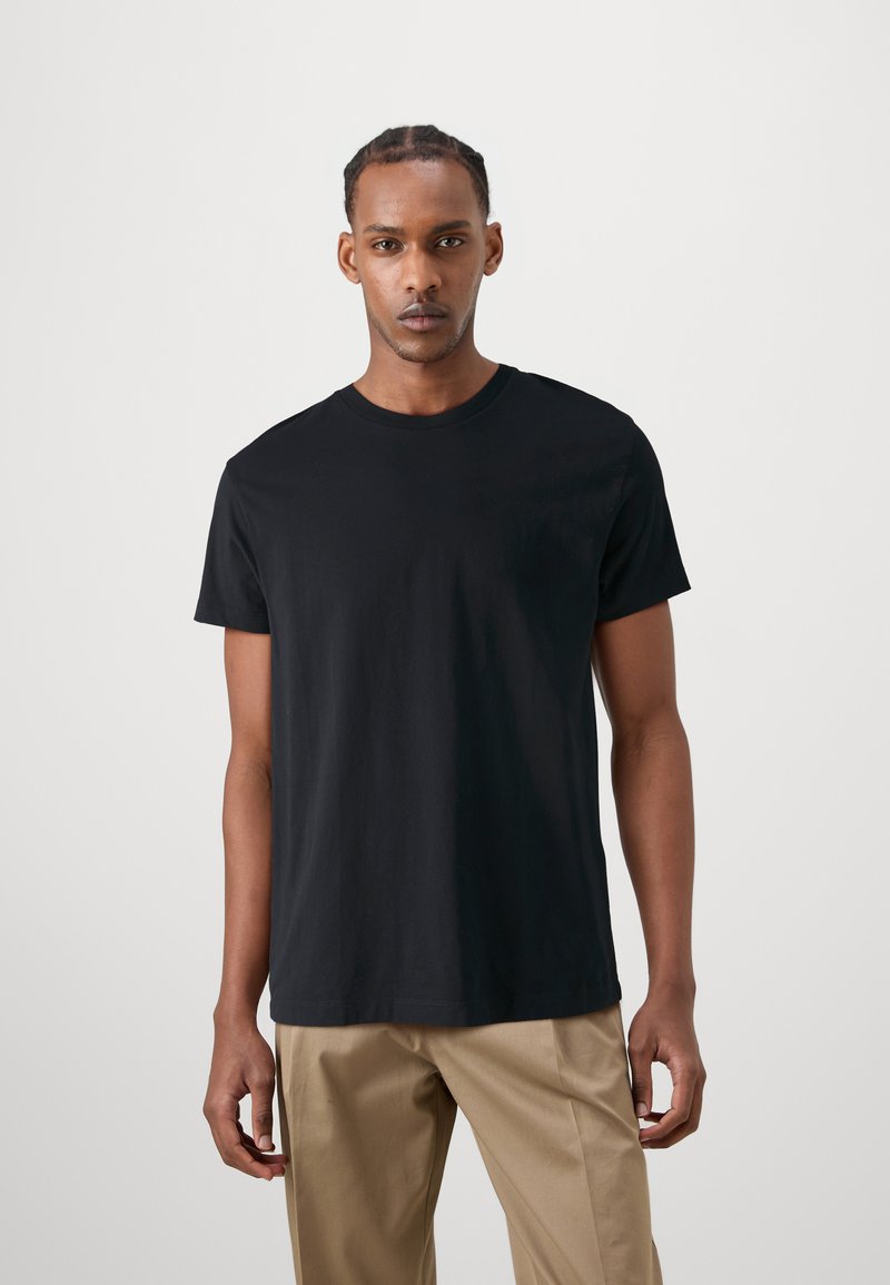 Schwarzes Baumwoll-T-Shirt mit rundem Ausschnitt und kurzen Ärmeln, im lockeren Schnitt. Glatte Textur, minimalistisches Design, keine sichtbaren Muster.