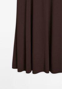 Hnědá sukně z lehkého materiálu s volným střihem. Vyznačuje se hladkým povrchem a zakřiveným, čistým lemem na spodním okraji.