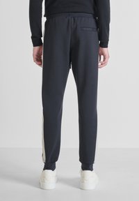 Marine joggings met een slim fit, voorzien van een contrasterende crèmekleurige streep langs de zijkant, elastische tailleband en een achterzak. Gecombineerd met witte sneakers.