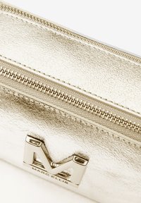 Metaal gouden pouch met een gestructureerde afwerking, bovenste ritsluiting en een zilveren logo dat de voorkant accentueert.