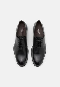 Schwarze Lederdressschuhe mit glatter Oberfläche, runder Zehenform, Schnürdesign und dezentem Stichdetail an den Seiten.
