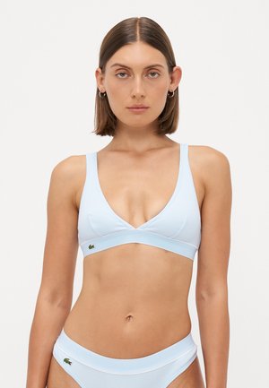 Light blue bikini top with a v-shaped design, ribbed texture, and a crossover front. Features a small green logo on the left side.