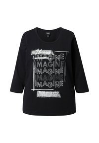 T-shirt nera in cotone con maniche a tre quarti, dotata di un design grafico testuale. Il testo include diverse ripetizioni della parola "IMAGINE" in font e texture variate.