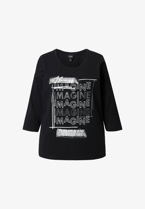 T-shirt nera in cotone con maniche a tre quarti, dotata di un design grafico testuale. Il testo include diverse ripetizioni della parola "IMAGINE" in font e texture variate.