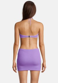 Paarse gebreide bikinibovenkant en rok met een gestructureerd ontwerp. De top heeft een halternek met een sluiting aan de achterkant, en de rok is nauwsluitend.