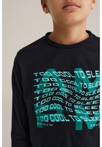 Dlhý rukáv čierne tričko s tyrkysov�ým grafickým textom, ktorý znie "PRÍLIŠ CHLADNÝ NA SPANIE" a súradnicami "52.1017'N 5.0477'E."