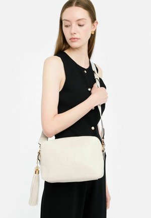 Borsa a tracolla in pelle crema con logo impresso, hardware dorato e lunga nappina. Tracolla regolabile e forma rettangolare.