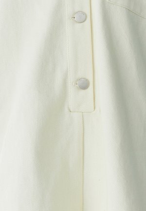 Light yellow fabric, textured with a ribbed pattern. Features silver snap buttons and a clean fold on the side. Minimalistic design.