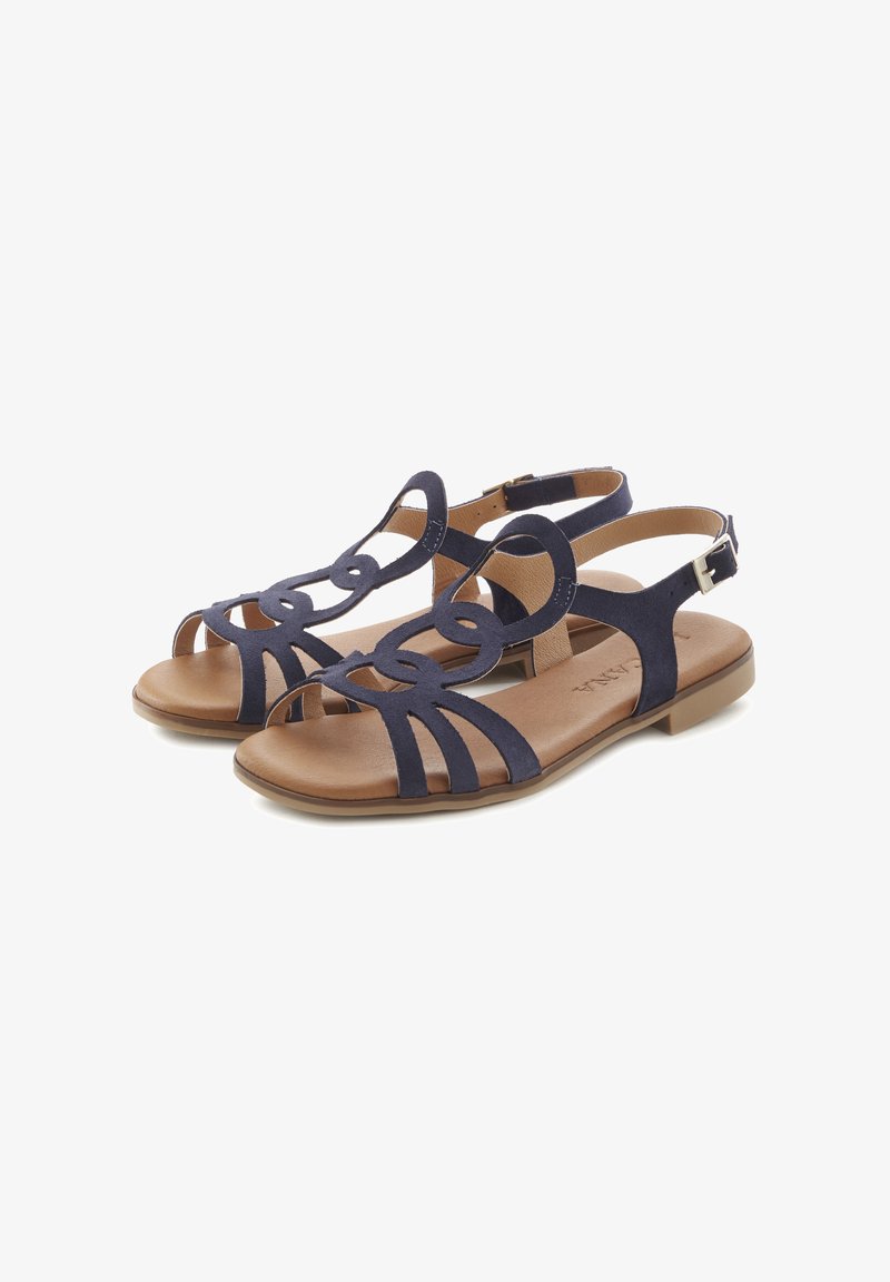 Marineblaue Wildledersandalen mit ausgeschnittenem Schlaufenmuster, offener Zehenpartie und verstellbarem Knöchelriemen. Flache braune Sohle mit glatter Oberfläche.