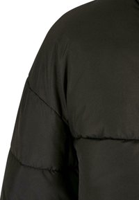 Black puffer jacket featuring a quilted design, smooth texture, and rounded shoulder shape; no visible hardware or embellishments.