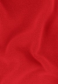Tissu tricoté rouge avec un motif texturé et côtelé. Le matériau semble doux et flexible, mettant en valeur des vagues et des plis subtils.