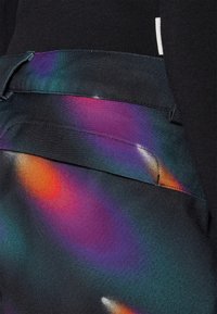 Mustal fabric, millel värviline, abstraktne muster, mis sisaldab halli lilla, apelsini ja teel. Sisaldab taskut ja õmmeldud detaile.