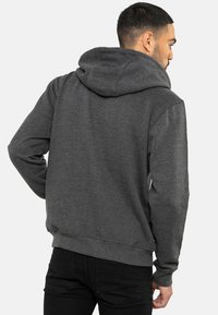 Sudadera gris oscuro con un bolsillo frontal, capucha con cordones, puños acanalados y dobladillo. Hecha de un tejido suave, con una textura lisa.