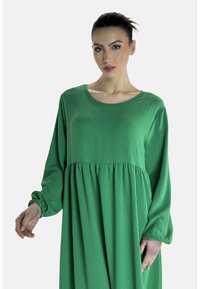Zielona, lekka sukienka z długim rękawem, okrągłym dekoltem i marszczonym pasem, z obszernymi rękawami zakończonymi elastycznymi mankietami.